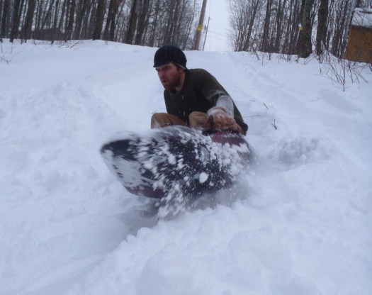 Kayak sledding behind out cabin.